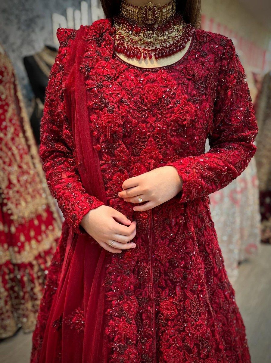 Macro of a deep red bridal gown bodice, dense floral beadwork and sequins covering the fabric, a matching necklace at the collar